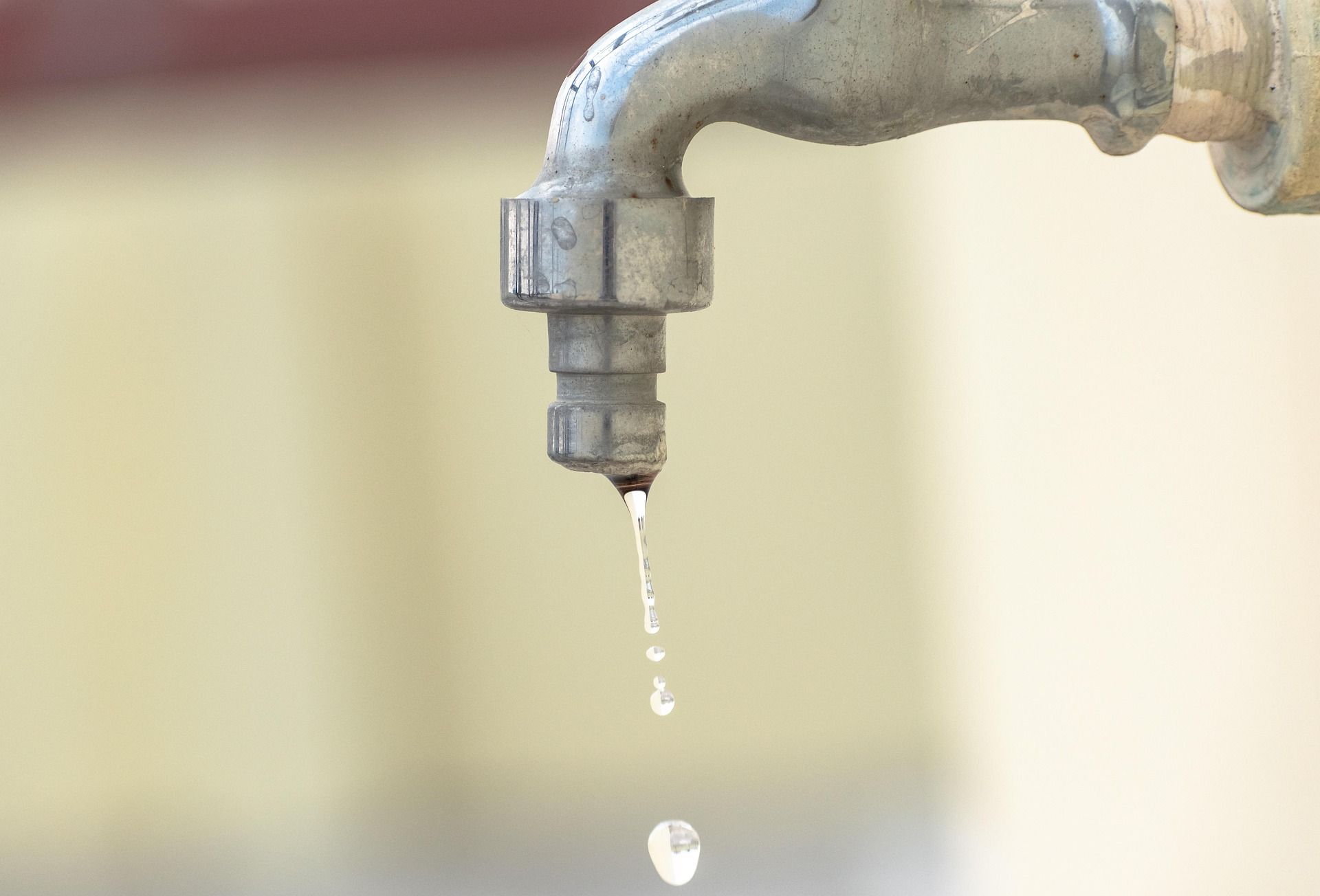 Grifo metálico goteando agua, ilustrando la necesidad de reparar fugas para el ahorro y eficiencia en el hogar.