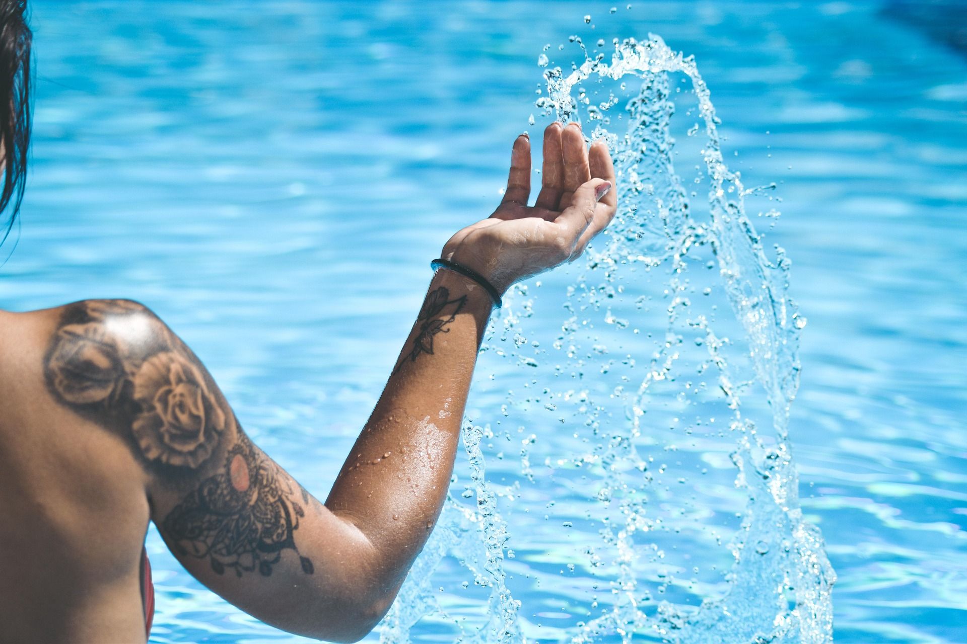 blog arquitectos 8 Mano femenina jugando con agua en una piscina, destacando el uso eficiente del agua en espacios recreativos.