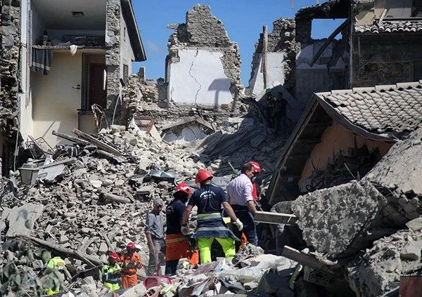 Equipos de rescate trabajando entre los escombros de edificios derrumbados tras un terremoto en España, resaltando la necesidad de arquitectura sismorresistente.