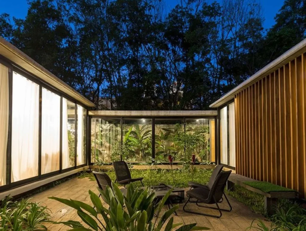 Patio interior biofílico en una residencia de lujo con vegetación integrada, madera natural y conexión visual con la naturaleza.