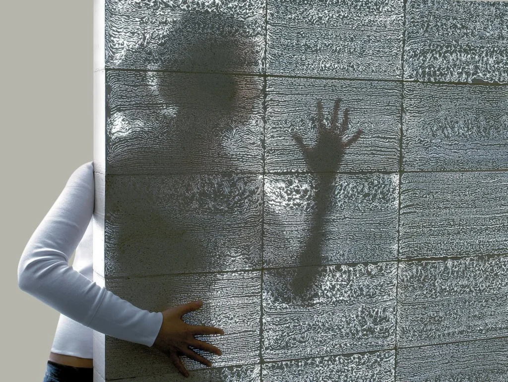 Muro de hormigón translúcido con silueta humana, ejemplo de nuevos materiales en arquitectura residencial de lujo.