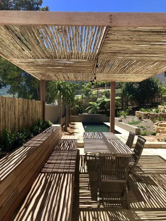 Pérgola de bambú con sombras lineales en patio, diseño dual estacional