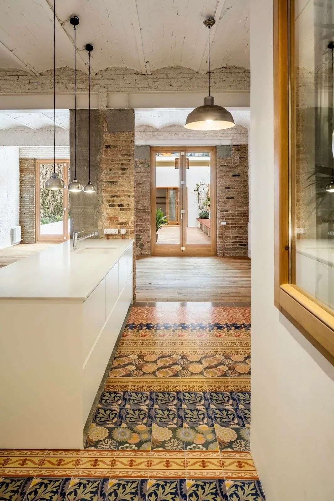 Cocina abierta con lámparas industriales y mosaico hidráulico.